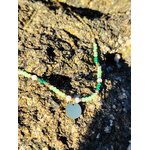 Collier doré avec cristaux verts et pendentif rond photographié sur une tranche de bois en Bretagne, esprit nature et élégance douce
