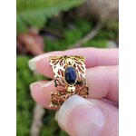 Bague dorée réglable en acier inoxydable, motif feuilles et pierre ovale lapis-lazuli, tenue entre les doigts; photo en Bretagne.