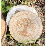 Plateau de pendule rond en bois gravé Arbre de Vie, posé dehors sur herbe et feuilles, repères Oui / Non / Peut-être / Redemande autour.
