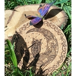 Dessous de plat rond en liège gravé d’une tête de loup avec arabesques, cercle décoratif et bordure celtique; photo dans l’herbe, papillon violet.