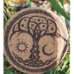 Dessous de plat rond en liège gravé arbre de vie avec soleil, lune et étoiles, bordure celtique; photo en extérieur dans l’herbe.