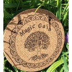 Dessous de plat rond en liège gravé “Magic Gaïa” avec arbre central et bordure mandala; photo en extérieur dans l’herbe, ombres de feuilles.