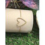 Bracelet chaîne fine en acier inoxydable doré, pendentif cœur ajouré; présenté sur support blanc, décor herbe et papillon violet en arrière-plan.