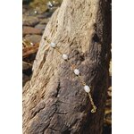 Bracelet chaîne dorée et nacre sur bois brut au bord de l’eau, éclat naturel, fluidité et style épuré