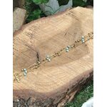 Bracelet doré en amazonite facettée posé en diagonale sur rondin en bois, bijou multi-rangs en acier inoxydable dans un décor végétal