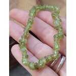 Bracelet péridot baroque tenu en main, éclats vert olive sur élastique pour clarté émotionnelle, joie tranquille et ouverture du cœur