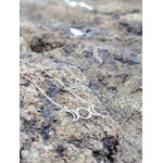 Collier fin triple lune argenté posé sur rocher granit en décor minéral sauvage, symbole des phases lunaires en Bretagne