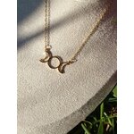 Collier triple lune doré porté sur buste beige en extérieur avec herbes en fond, bijou lunaire en acier inoxydable