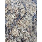 Collier triple lune en acier inoxydable sur rocher granit en extérieur, symbole lunaire au style mystique photographié en Bretagne