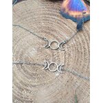 Pendentif et bracelet triple lune dorés posés sur une tranche de bois avec reflets multicolores, duo de bijoux symboliques