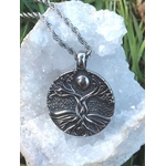 Pendentif Yggdrasil sur fond nature avec géode blanche et touches de vert, symbole de continuité, de vitalité et de recentrage