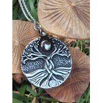 Pendentif Yggdrasil argenté sur chaîne, posé sur champignons en bois et herbe, bijou symbolique d’ancrage et d’élan vital