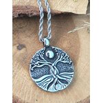 Collier arbre de vie rond sur bois clair avec touche de verdure, stabilité émotionnelle, recentrage et présence solide