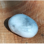 Pierre roulée howlite blanche marbrée de gris polie sur tranche de bois, reflets doux et veinures nuagées, pierre naturelle associée à la tranquillité, à la justesse d’expression et à la lucidité.