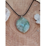 Pendentif en garniérite vert-bleuté sur cordon noir, pierre polie posée sur bois avec petits galets blancs, bijou en pierre naturelle évoquant le recul, la sérénité et l’équilibre intérieur.