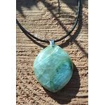 Pendentif en garniérite vert d’eau sur cordon noir, pierre polie marbrée posée sur bois brut, bijou en pierre naturelle associé à la stabilité, au calme du mental et à la présence à soi.
