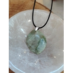 Pendentif garniérite verte sur cordon noir avec bélière argentée, posé sur une géode de quartz blanc, pierre naturelle reliée au calme intérieur, à la finesse émotionnelle et à l’ancrage.