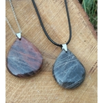 Deux pendentifs goutte en pierre de lune noire, l’un sur chaîne argentée et l’autre sur cordon noir, posés sur une tranche de bois, bijoux en pierre naturelle associés au recentrage, à la douceur intérieure et à l’équilibre émotionnel.