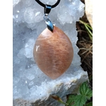 Pendentif goutte en pierre de soleil sur cordon noir, posé sur cristaux blancs et mousse, bijou en pierre naturelle associé à la chaleur intérieure, à l’élan positif et à la confiance douce.