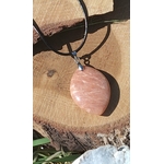 Pendentif goutte en pierre de soleil sur cordon noir, posé sur tranche de bois avec cristaux, bijou en pierre naturelle évoquant l’enthousiasme, la volonté et la lumière intérieure.