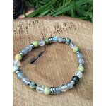 Bracelet vampire énergétique sur rondin de bois avec feuillage en arrière-plan, perles naturelles pour tri émotionnel, calme vigilant et protection douce