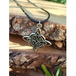 Collier nœud de sorcière argenté sur cordon noir, posé sur écorce et mousse avec feuillage, ambiance forêt et énergie protectrice