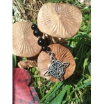 Bijou de rétroviseur nœud celte : perles de tourmaline noire et pendentif triquetra argenté, posé parmi champignons beige et feuillage vert. Création Magic Gaïa, pour protection, ancrage et sérénité.