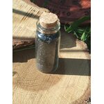 Sel noir ritualisé fait maison en flacon en verre avec bouchon liège, photo sur rondin de bois et décor naturel; usage rituel protection, purification, ancrage, coupure des énergies lourdes et soutien des intentions.