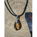Pendentif citrine sur cordon noir, gros plan sur décor bois clair, pierre naturelle évoquant la volonté, la joie de vivre et la stabilité lumineuse.