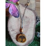Pendentif Arbre de Vie en bois rond gravé sur cordon noir avec perles bois, posé sur tranche de bois et fleur violette, création nature au symbole d’enracinement