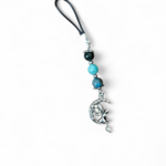 Bijou de téléphone création Magic Gaïa sur fond blanc, cordon noir, perles amazonite, aqua terra et agate mousse, breloque fée argentée, apaisement, communication, ancrage, équilibre émotionnel.
