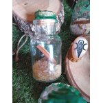 Fiole spell jar abondance Magic Gaïa, cire verte au bouchon, riz au fond et cannelle, décor nature mousse, tranche de bois en arrière-plan