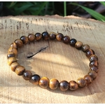 Bracelet Œil de Tigre 6 mm sur élastique, perles brun doré sur rondin de bois en décor naturel, discernement et assurance.