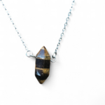 Pendentif pointe œil de tigre sur chaîne en acier inoxydable, photo sur fond blanc, pierre naturelle reliée au courage, au recentrage et à la confiance tranquille.