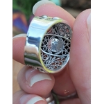 Bague argent 925 large anneau filigrane vue arrière tenue entre les doigts fond flou multicolore intentions associées protection ancrage stabilité force intérieure