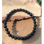 Bracelet Onyx noir en perles rondes sur tranche de bois texturée, ombre visible, concentration, structure et maîtrise intérieure.