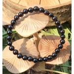 Bracelet Onyx noir en perles lisses rondes, vue du dessus en décor naturel, recentrage, maîtrise intérieure et solidité émotionnelle.