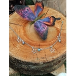 Chaîne de cheville création Magic Gaïa en acier inoxydable, étoiles et perles Aqua Aura, posée sur un rondin de bois avec un papillon coloré, pour une touche de fraîcheur et confiance.