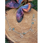 Chaîne de cheville création Magic Gaïa en acier inoxydable, étoiles et perles Aqua Aura, posée sur rondelle de bois avec papillon bleu-violet, pour légèreté et confiance.
