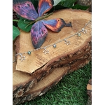 Chaîne de cheville création Magic Gaïa en acier inoxydable avec étoiles et perles Aqua Aura, posée sur rondin de bois avec papillon bleu-violet et mousse, pour une touche de légèreté.