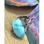 Bague réglable en argent avec larimar bleu lagon, posée sur rondin de bois près d’une aile de papillon irisée, pour douceur, apaisement et expression.