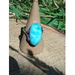 Bague larimar réglable en argent sur cône en kraft, posée sur table en bois au soleil avec feuillage flou, pour calme, clarté et confiance.