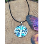 Pendentif arbre de vie en abalone et argent 925 sur cordon noir, posé sur rondin de bois avec papillon violet en arrière-plan, bijou en nacre naturelle évoquant l’expression sincère, la sérénité et l’harmonie intérieure.