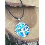 Pendentif arbre de vie en abalone et argent 925 sur cordon noir, posé sur tranche de bois près d’un papillon peint, bijou en nacre naturelle associé à l’apaisement, à la présence à soi et à la confiance intérieure.