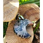 Pendentif lune en rhodonite rose marbrée de noir, posé sur champignons beige avec feuillage vert en fond, bijou en pierre naturelle associé au réconfort affectif, à la paix intérieure et à la douceur relationnelle.