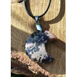 Pendentif lune en rhodonite sur cordon noir, posé sur bois brut avec ombre douce, bijou en pierre naturelle associé à la douceur du cœur, au recentrage et à l’harmonie émotionnelle.
