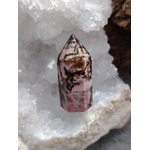 Pointe de rhodonite rose veinée de noir posée dans un bol de sélénite blanc, lumière douce et fond sombre, pour apaiser le cœur et soutenir l’équilibre émotionnel.
