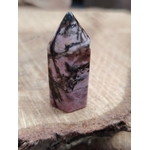 Pointe de rhodonite rose veinée de noir posée sur une tranche de bois, lumière douce et fond flou, pour apaiser le cœur et équilibrer les émotions.