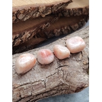 Quatre pierres roulées en pierre de soleil, posées sur une tranche de bois à l’écorce brute, lumière douce, pour la joie, la confiance et l’élan intérieur.