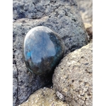 Galet de labradorite aux reflets bleu pétrole calé entre rochers de granit en Bretagne, pierre naturelle évoquant la profondeur intérieure, l’intuition et la stabilité émotionnelle.